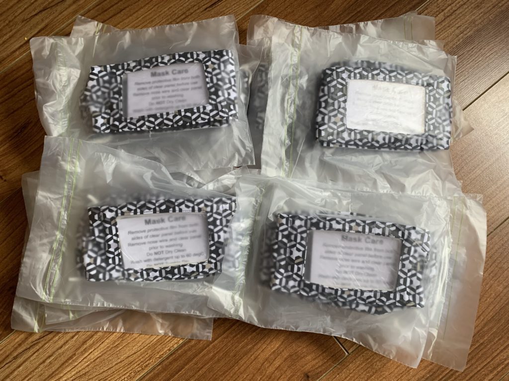 Shows masks packaged in bags with washing instructions ready for delivery.